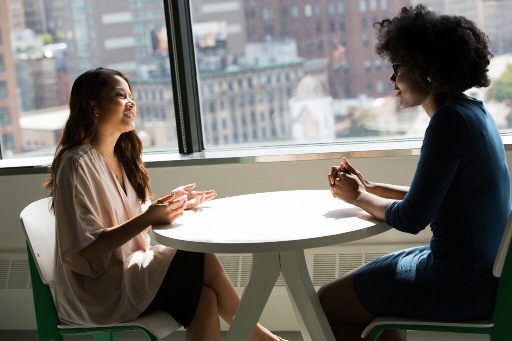 pexels-photo-1181717-1181717 Two professional women having a discussion at a desk in a bright office setting.